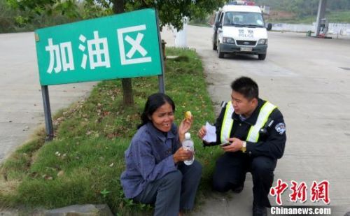 图为民警给误上高速行走的越南籍女子送上食品并试图沟通了解情况。 周利朔 摄