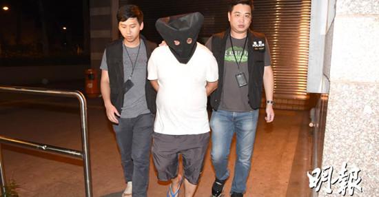 涉嫌斩人男子被警方拘捕，黑布蒙头，带回警署。图自香港《明报》网站