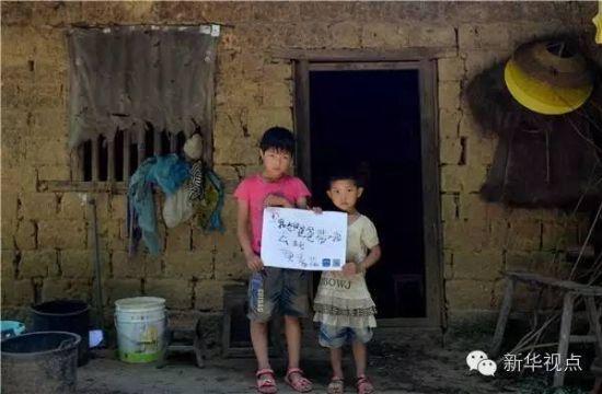 在湖南省邵阳县黄荆乡，黄春花和妹妹在纸上写下自己的心愿“我想爸爸带我去玩”(7月28日摄)。