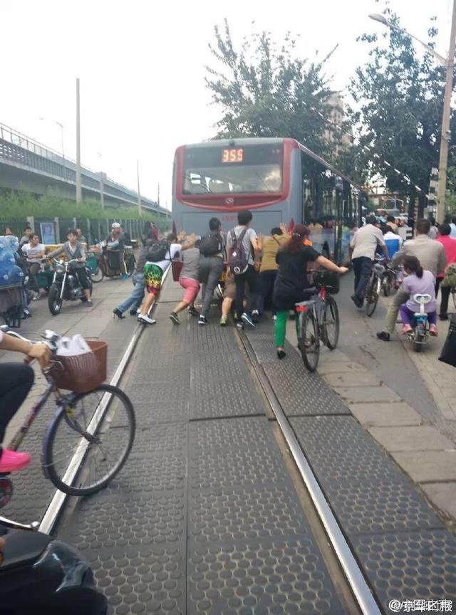 北京一公交因故障在铁轨上停车 众人合力推车