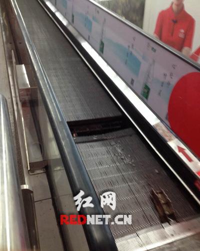 手扶电梯踏板两块断裂，还有金属碎片在断裂处周围。