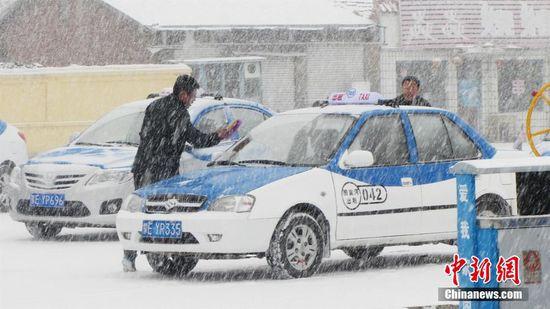 呼伦贝尔市牙克石市图里河镇，一位出租车司机在雪中清理车窗上的积雪。