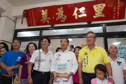 宋楚瑜25日上午抵达金华小区活动中心时，不仅受到大批小区民众热烈欢迎，还与乡亲们在他担任省长时致赠的“里仁为美”匾额下留影。(图自台湾“中时电子报”)