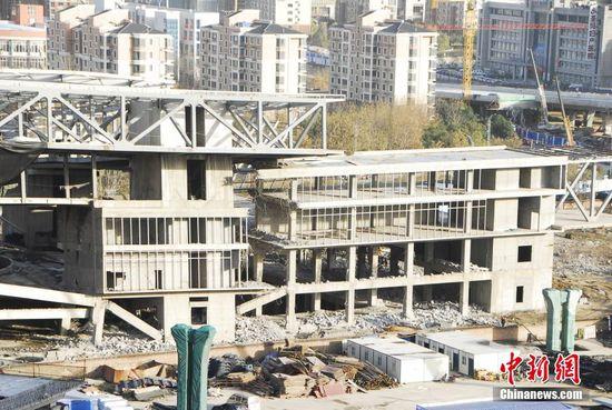 12月2日，河南省郑州市，据《中国经营报》此前报道，位于郑东新区的“中原之门”大楼已经烂尾3年多，由于农业路改造，“中原之门”即将被拆。时隔两月，媒体记者再探访，发现这座曾投资规模近1.8亿元的“烂尾之门”正被拆除中，建筑主体已经倾斜，墙柱钢筋暴露，现场近10台大型钩机正在对它进行拆除。