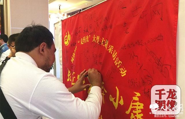 参加“长征路上奔小康”大型主题采访活动甘肃站的网络媒体记者在红旗上签下自己的名字。千龙网记者 马文娟 摄_副本