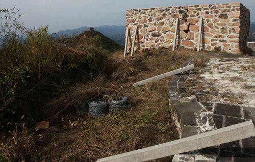 由于物料太多人手不够，当地村民只能把物料分若干小批从长城上往山下运。图为停工现场尚未运走的水泥桩子和铁丝网。 受访者供图