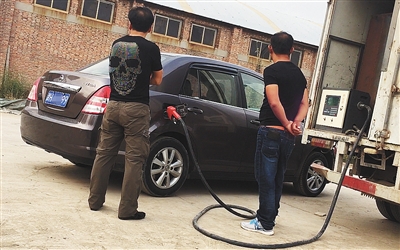 9月26日一早，在菁华苑小区西侧一个简易围挡围成的院内，一辆黑加油车正在给一辆私家车加油。