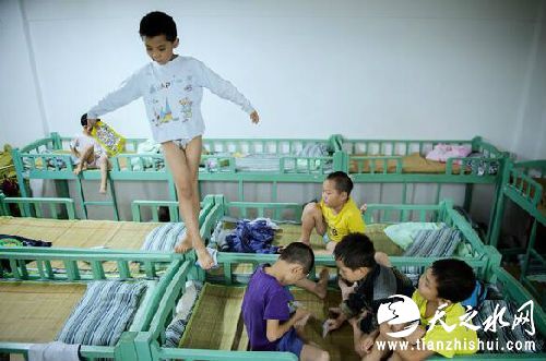 在中国湖南的一个寄宿学校宿舍里，一个男孩站在床栏上练平衡，其他孩子在打牌。（图片来源网络）
