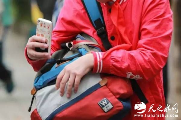 一小学放学后，一位男生刚出校门便从包里拿出手机。