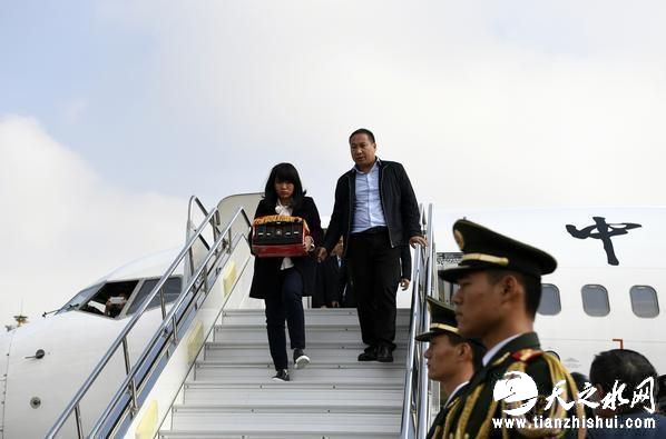 10月16日，火海救人英雄王锋的妻子潘品（左）手捧丈夫的骨灰到达河南南阳机场。