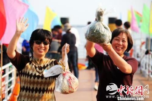 资料图：两位女游客手举获赠的阳澄湖大闸蟹，开心不已。 　李克祥 摄